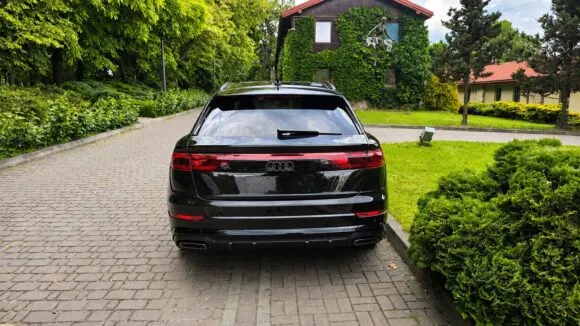 Czarne Audi Q8 od tyłu na brukowanym podjeździe przed domem