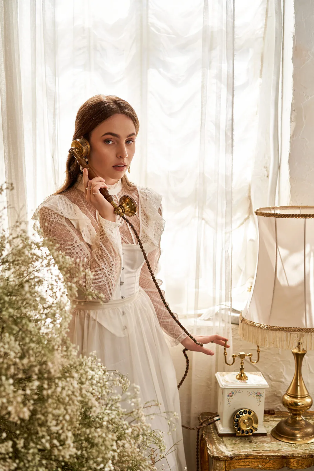 Kobieta w białej sukni nagrywa życzenia przez stylowy telefon retro