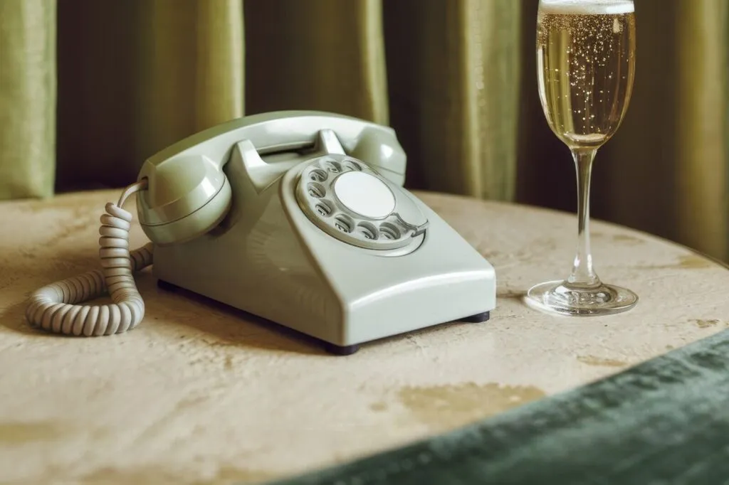 Zabytkowy telefon na stoliku obok kieliszka szampana