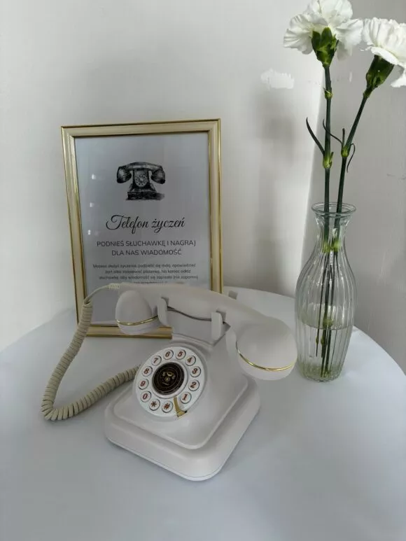 Biały telefon życzeń na okrągłym stoliku przykrytym obrusem